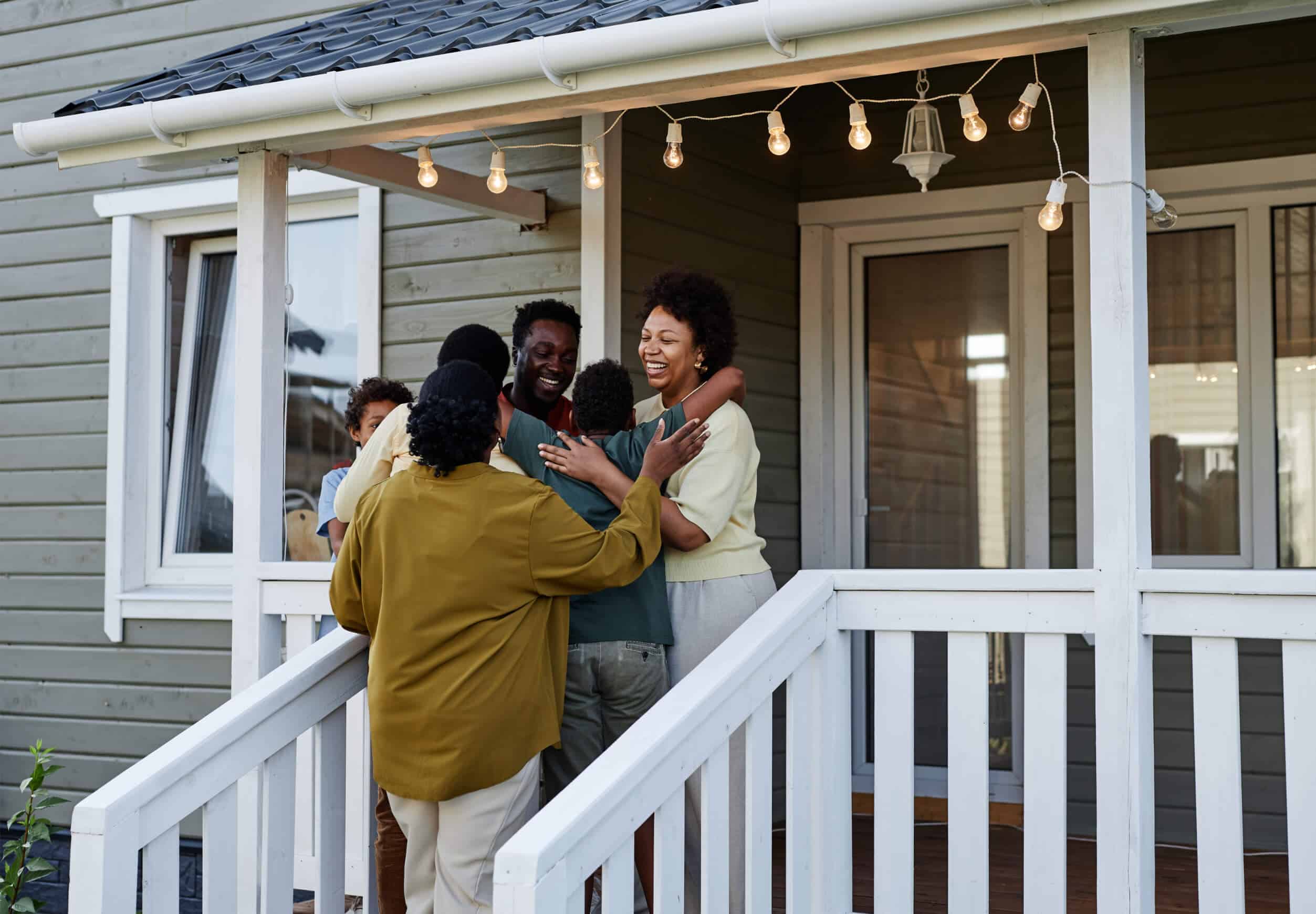 Small family gathered on porch in front of cottage home