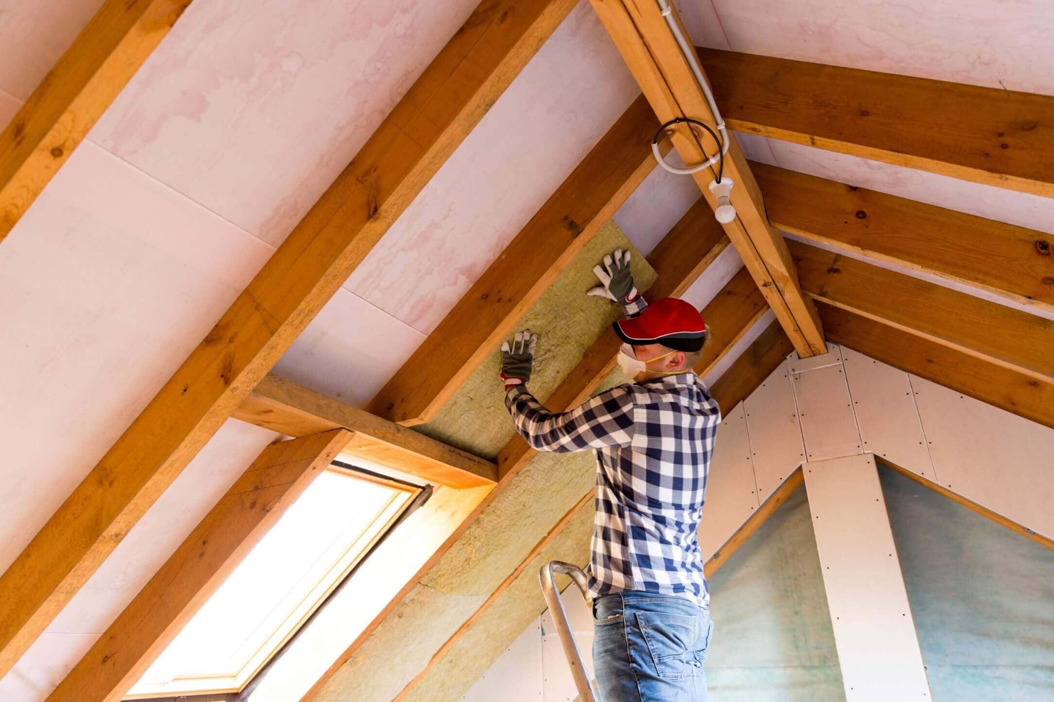 Construction worker holds board between roof frame in new home