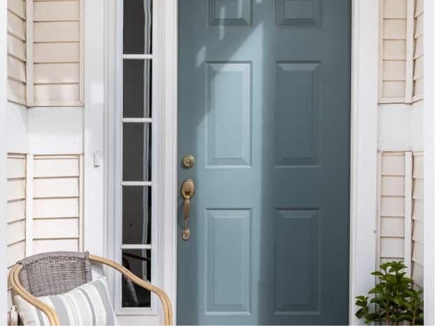 Front door of house with a single wicker chair for sitting